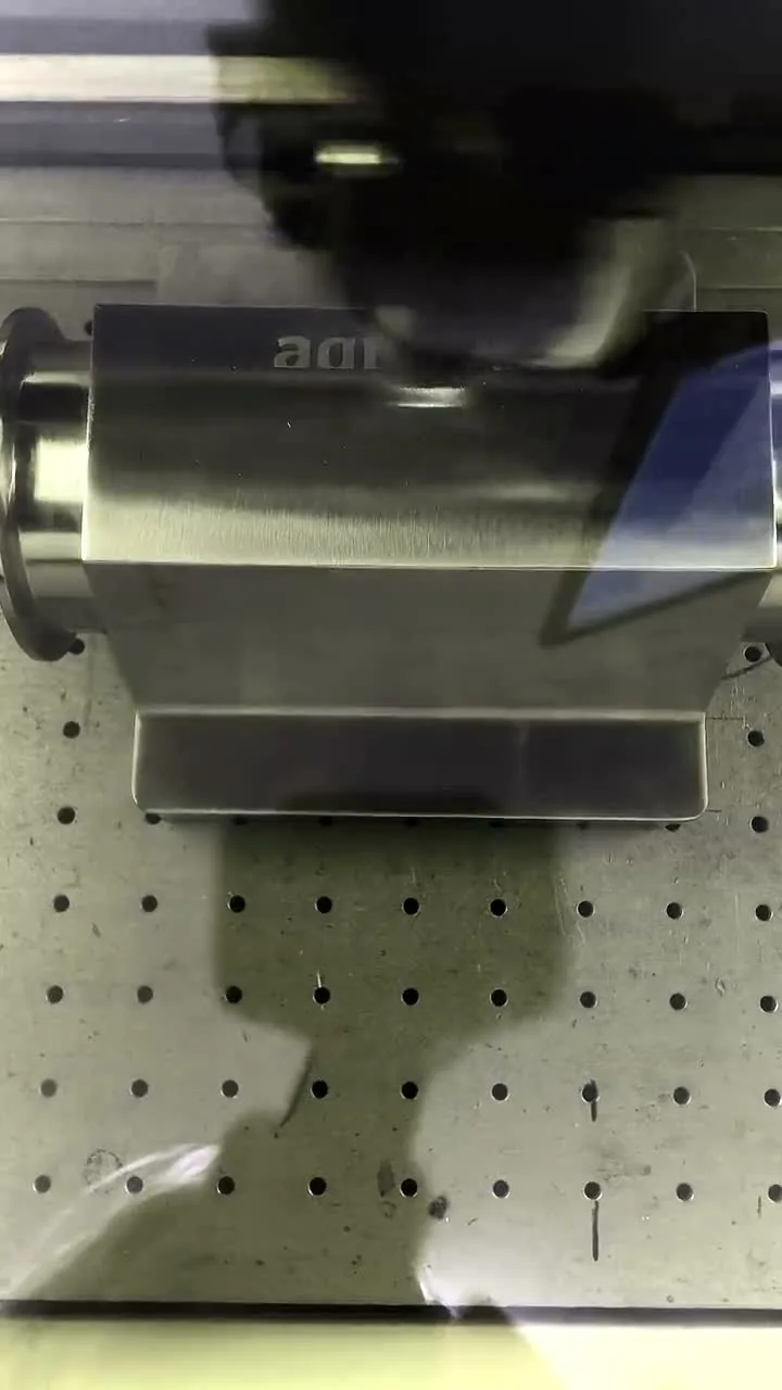 A stainless valve body being laser engraved, seen through the marker&rsquo;s safety window