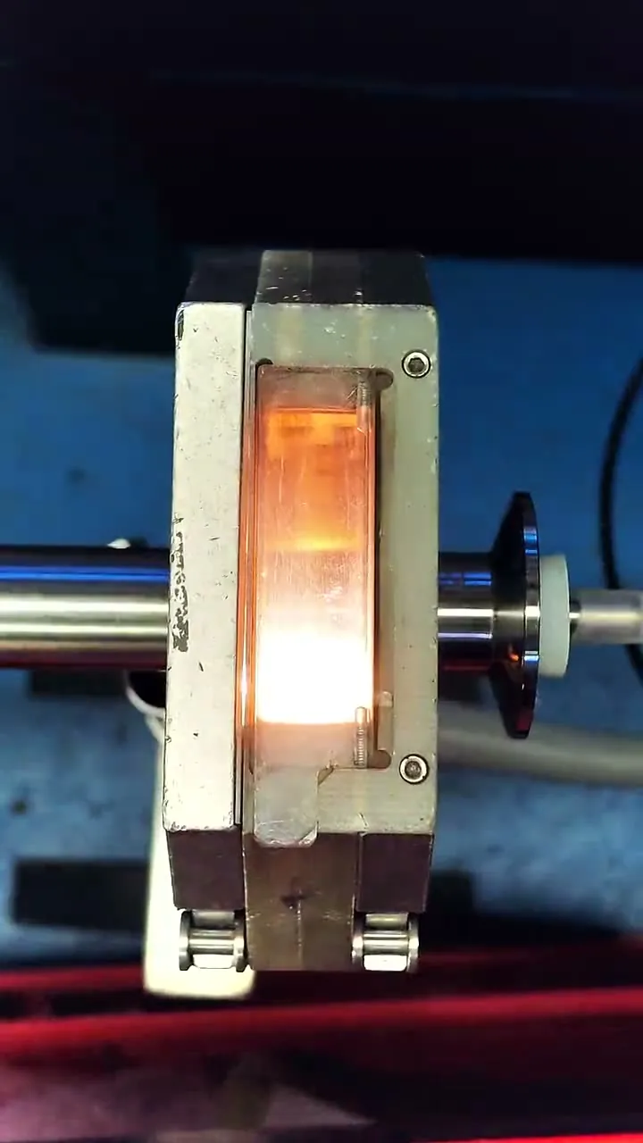 A closed orbital weld head clamped on stainless tube, the arc glowing through the inspection window